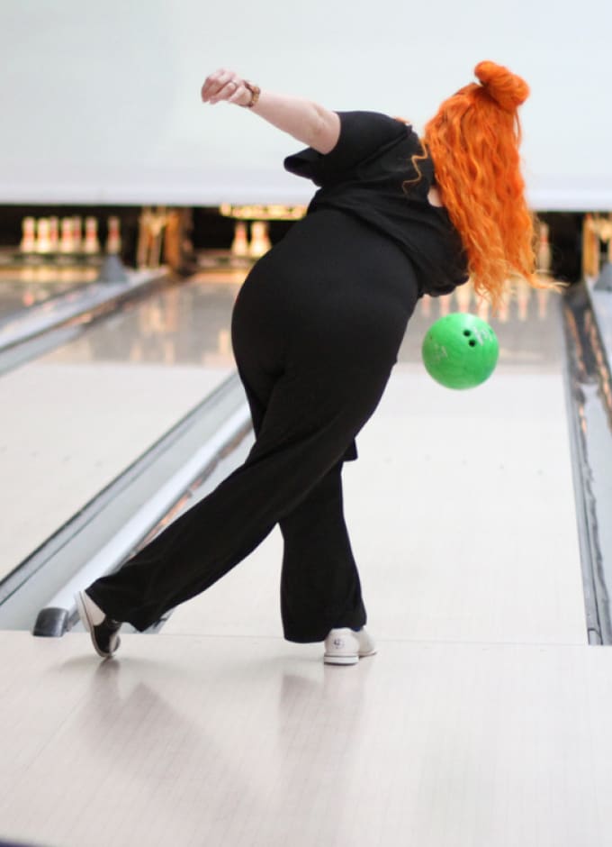 Kvinde skyder kugle ned ad bowling bane